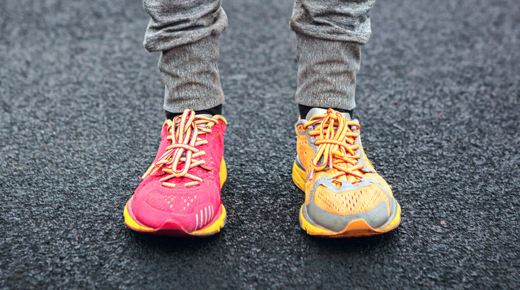 Person standing on a roadway wearing unique sneakers.