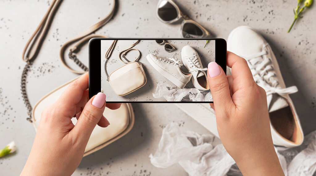 Woman photographing sustainable sneakers with smartphone for eco-friendly spring fashion content.