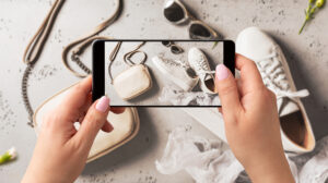 Woman photographing sustainable sneakers with smartphone for eco-friendly spring fashion content.